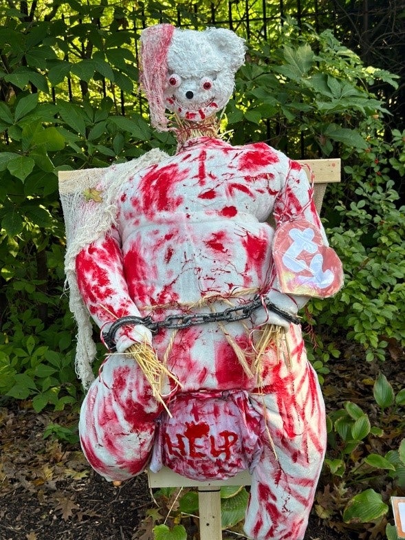 A scarecrow designed to look like a bloody Beanie Baby bear. 