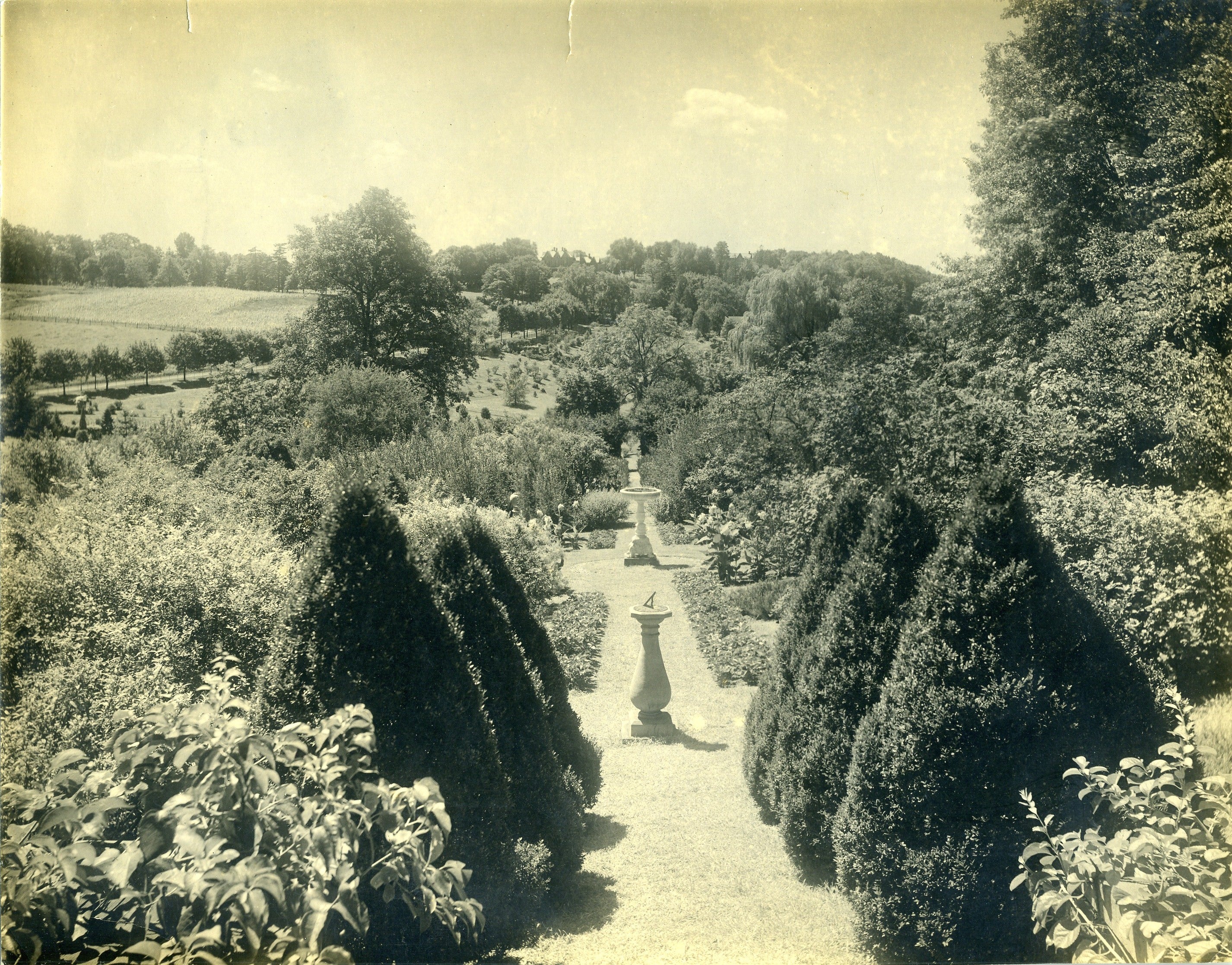 A black-and-white photograph of a garden with fountains.