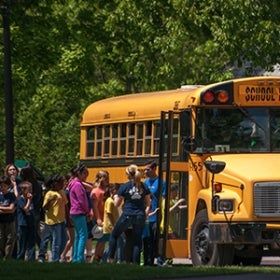 A group of young students wait in a line to board a school bus.