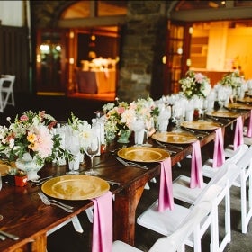 A long banquet table decorated with flowers and place settings. 