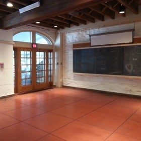 An empty classroom with wooden French doors and a blackboard. 