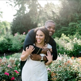 A bride and groom hugging each other in a rose garden. 