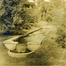 A black and white photo of a long fountain. 