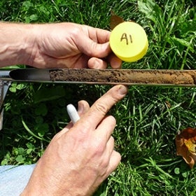 A closeup of two hands holding a soil sample and performing a test. 