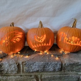 Three carved Halloween pumpkins lit up with string lights. 