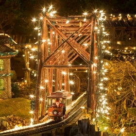 A miniature train display lit up and decorated for the holidays.