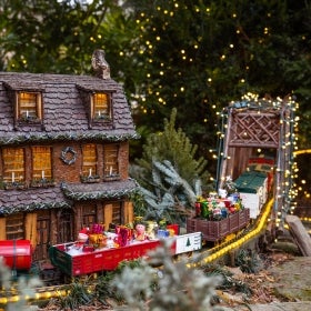 A miniature model train display decorated with lights for the holidays.