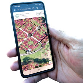 A hand holding a mobile device with an garden map on display. 