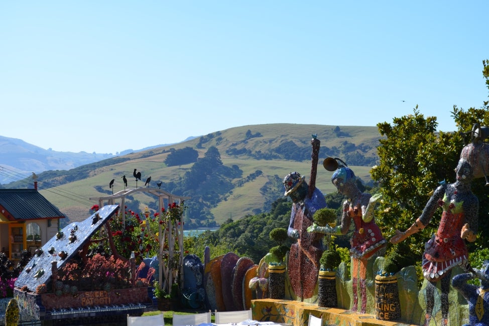 Oversized, colorful statues of people playing instruments with green hills and a blue sky in the background. 