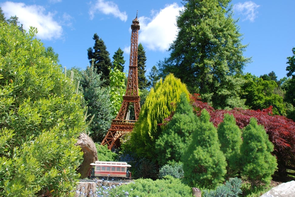 A miniature replica of the Eiffel Tower in a miniature train display in a public garden. 