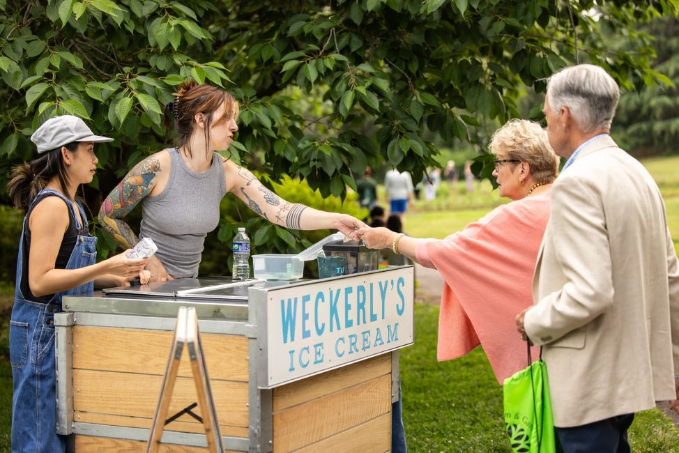 An ice cream vendor in an outdoor space selling ice cream sandwiches.