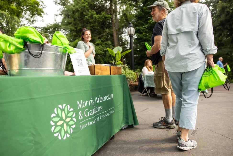 People standing near a Morris Arboretum & Gardens registration table.