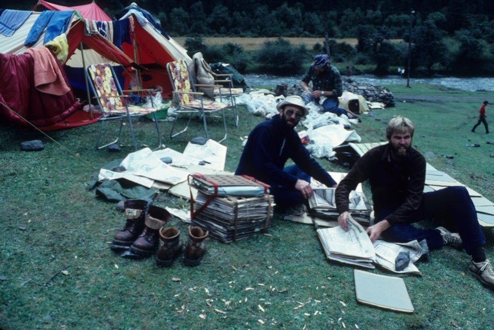 Two men sit outside at a campsite. 