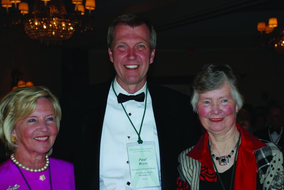 A man and two woman in formal clothing smile for the camera. 