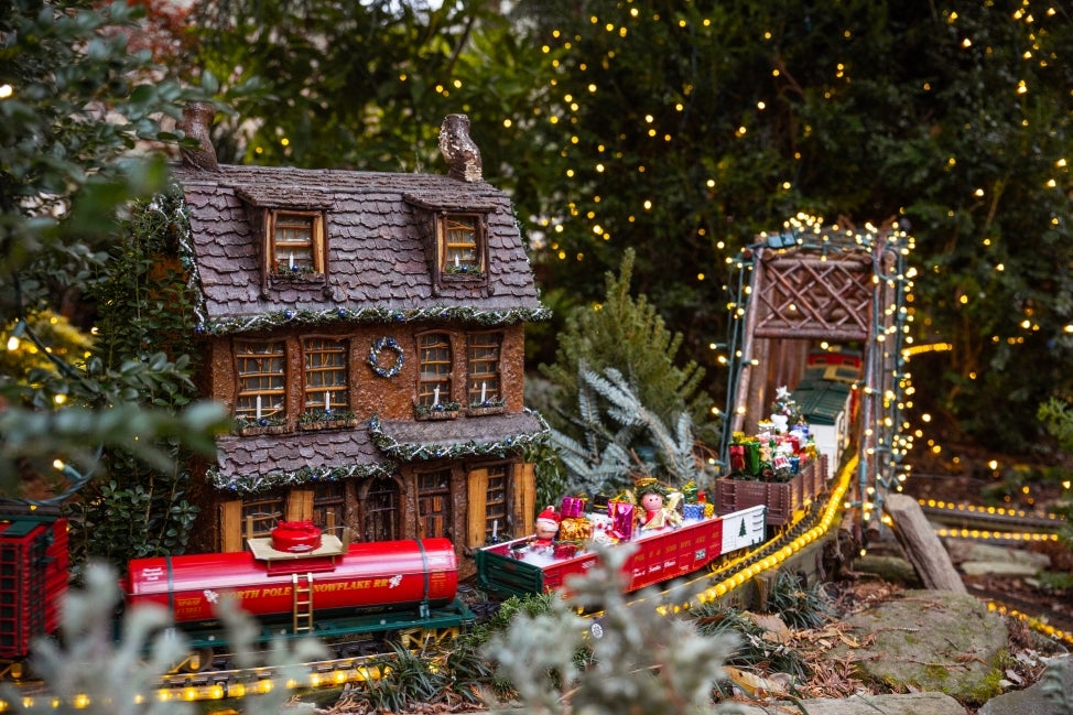 A miniature train display decorated in holiday lights. 