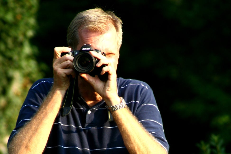 A man aims his camera toward you. 