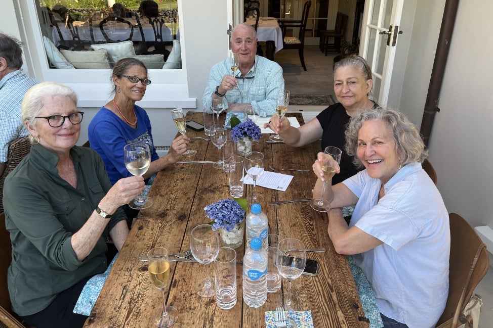 A group of people sit around a table drinking wine. 