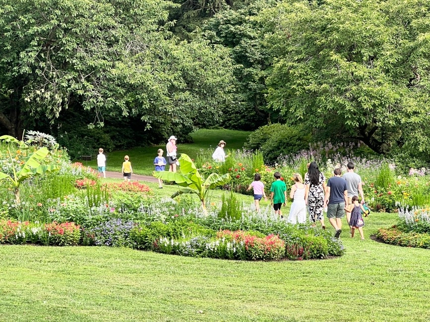 People walking through paisley-shaped garden beds in bloom with colorful flowers. 