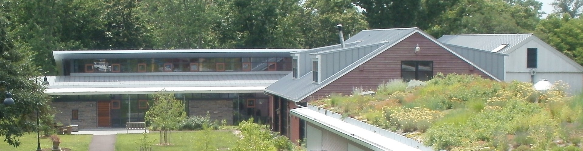 A one-story sustainable building with trees growing in the background.