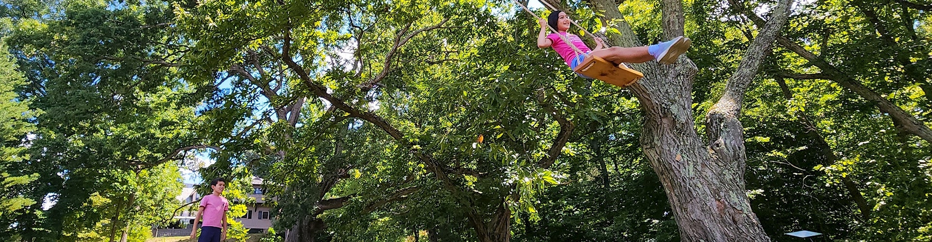 a young girl swinging and a young boy waiting