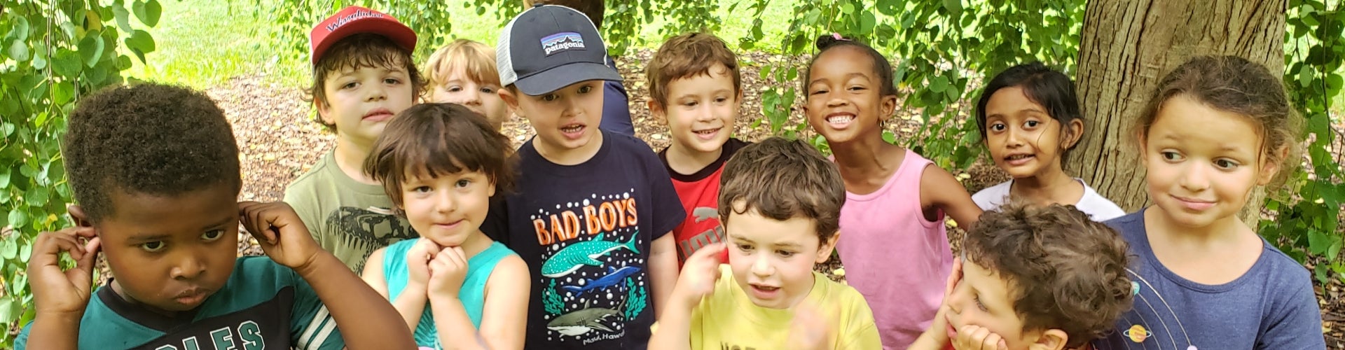A group of children stand outdoors and make faces at the camera.