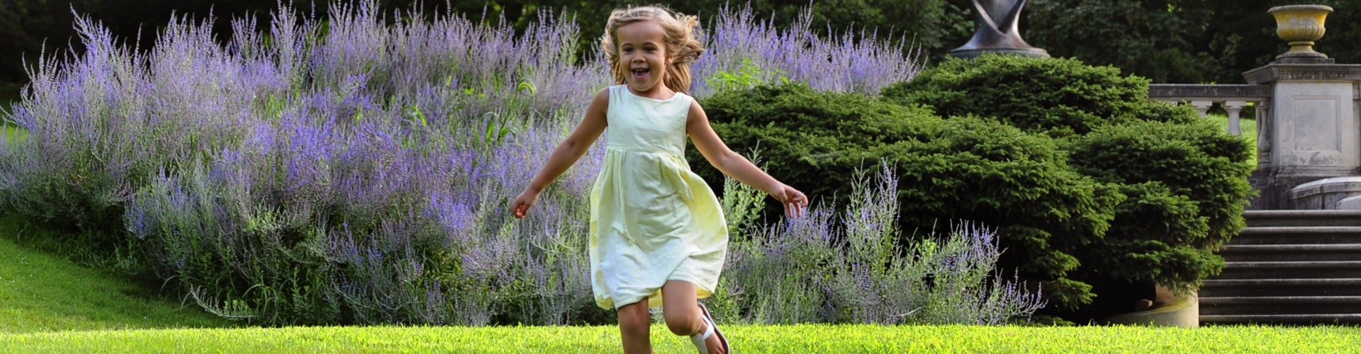 A young girl running through a public garden.