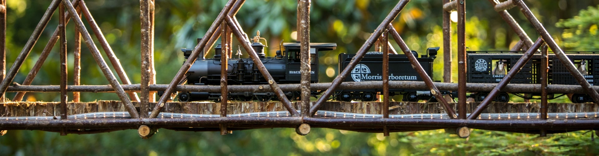 A model train rides through a wooden tressle.