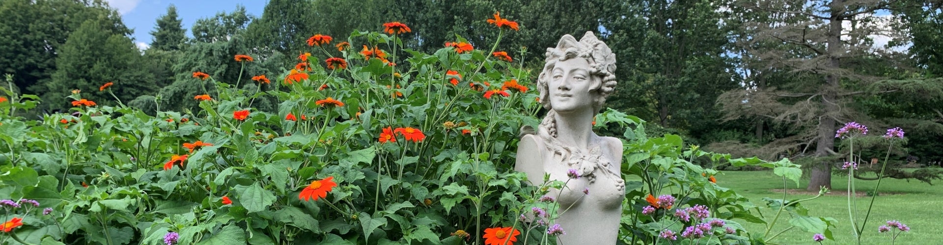 A statue of a Greek nymph in a flowering garden.