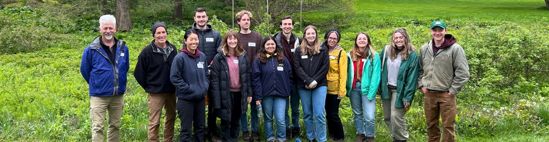 A group of interns stand in an outdoor green space and smile for the camera. 