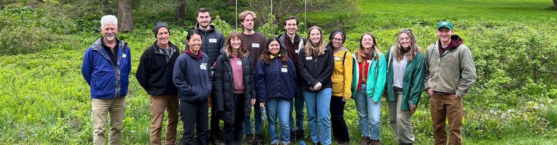 A group of interns stand in an outdoor green space and smile for the camera.