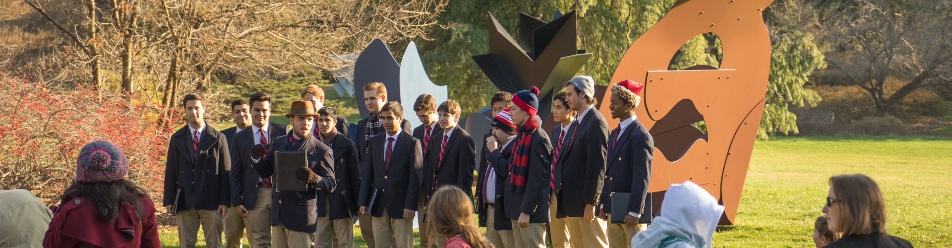 A glee club stands outside preparing to sing. 