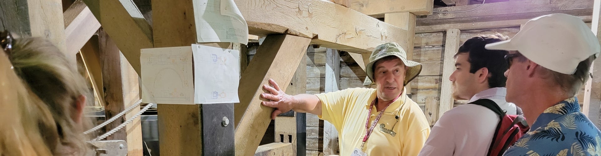 A man in a yellow shirt and bucket hat talks with several people.