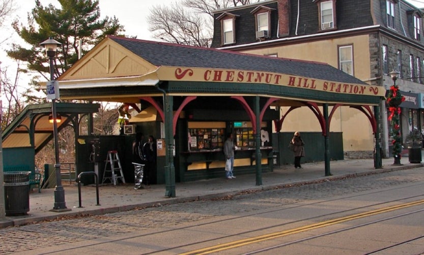 A yellow train station pavilion with the words Chestnut Hill Station in red letters