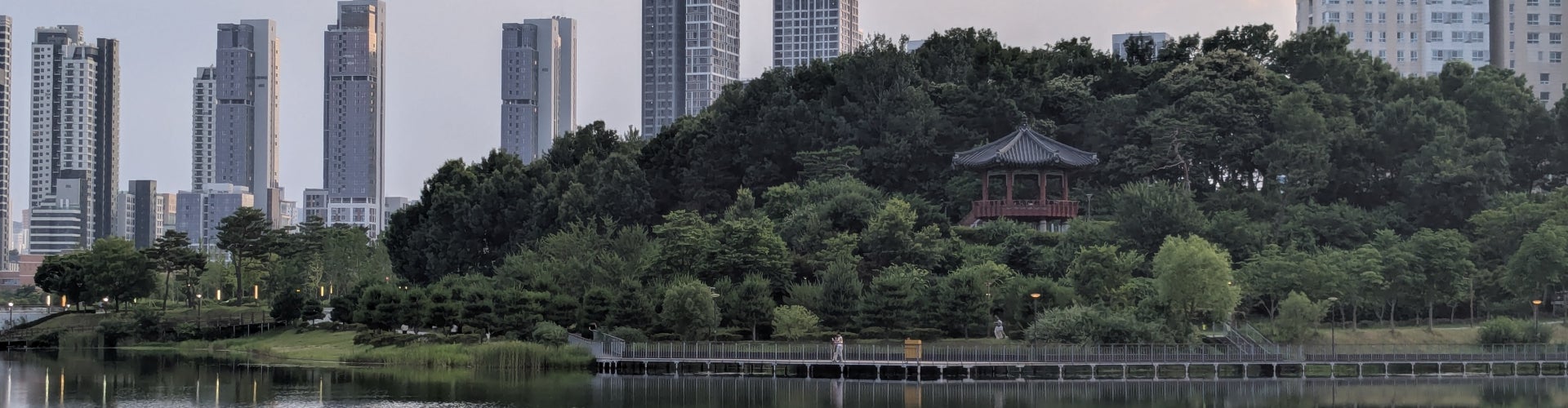 A city park in Sejong, South Korea with greenery, water, and building. 