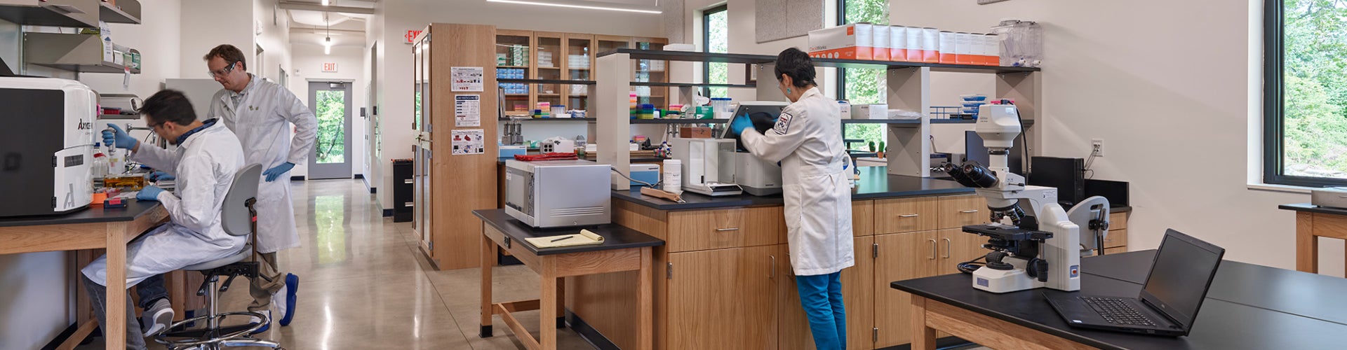 Three scientists wearing white lab coats working in a laboratory.