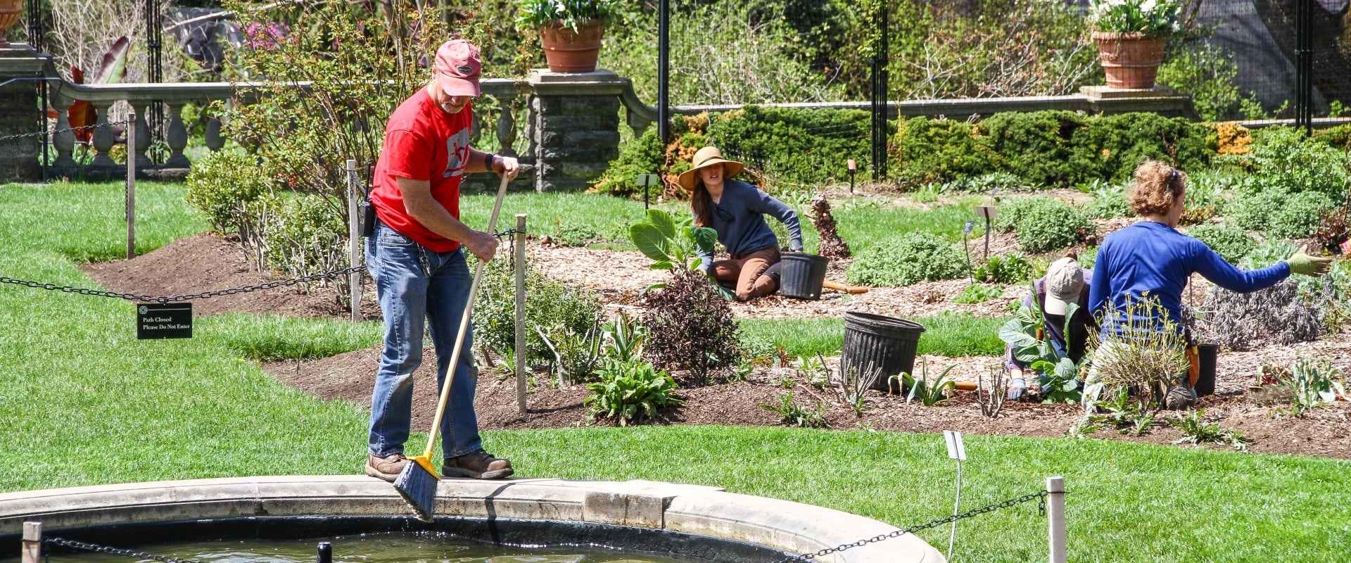 A man and two woman working in a flower garden. 