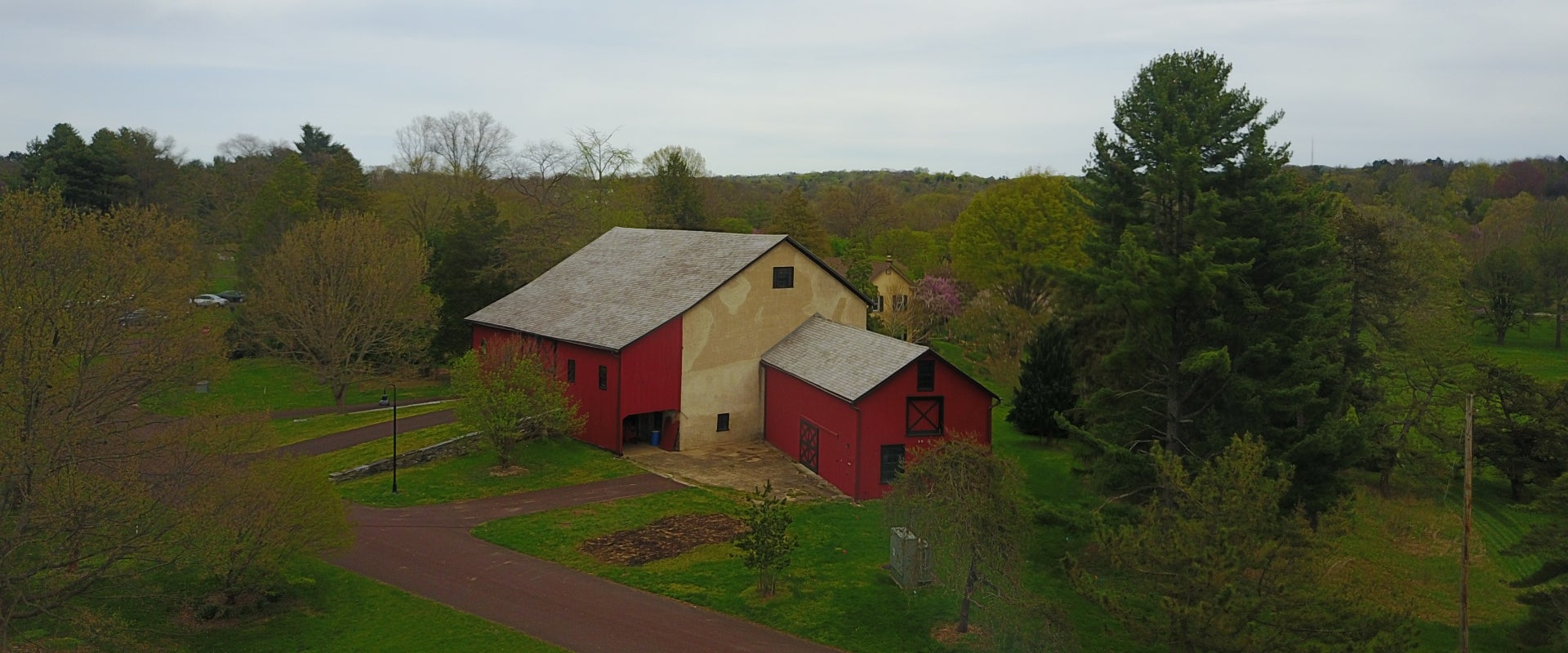 An aerial view of a red barn among trees.