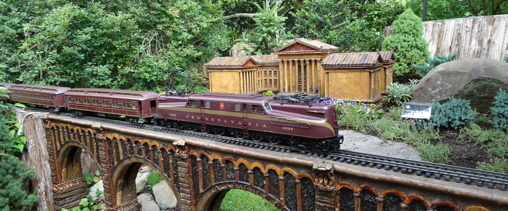 A model train rides along a track with a miniature replica of the Philadelphia Art Museum in the background. 