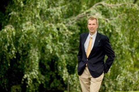 Paul Meyer standing in front of green foliage.