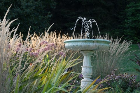 A marble fountain surrounded by pink and tan foliage.