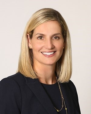 A white woman with blond hair smiles at the camera. 