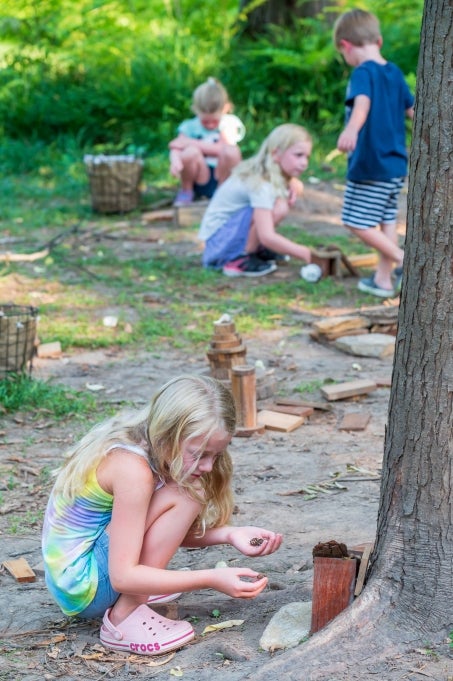 A young girl builds a fairy house out of natural materials. 