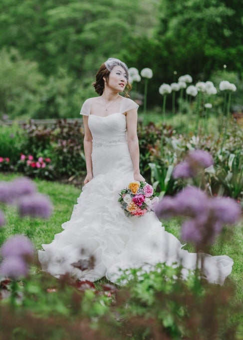 A bride stands in a blooming garden. 