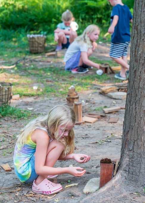 A young girl builds a small house for fairies made out of natural materials.