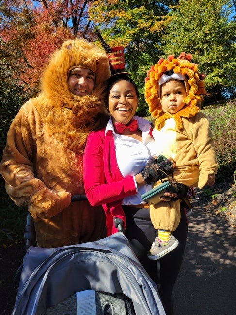 A family of two adults and one child dressed up for Halloween. 