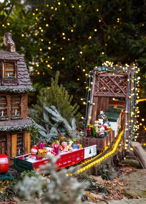 A model train display decorated in holiday cars and twinkle lights. 