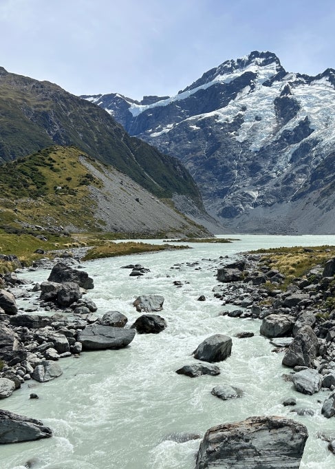 A flowing body of water on a rocky landscape with mountains in the background.