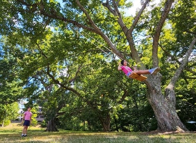 a young girl swinging and a young boy waiting