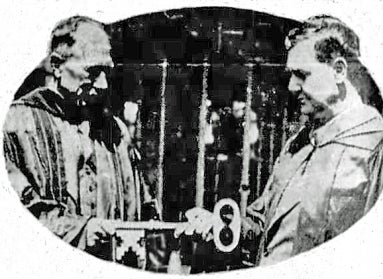 A black and white photo from 1933 of one made handing a large key to another man.