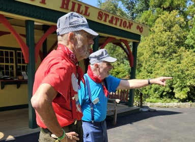 Two men wearing blue and white striped train engineer caps and red bandannas